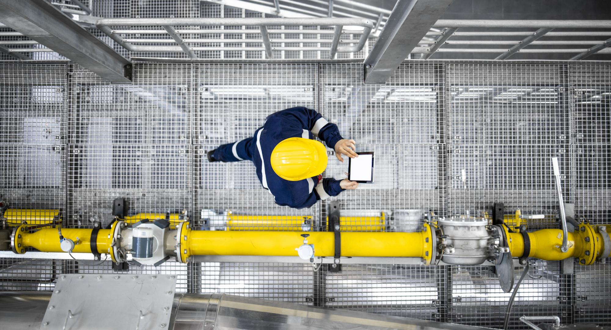 Top view of refinery worker walking by gas pipes