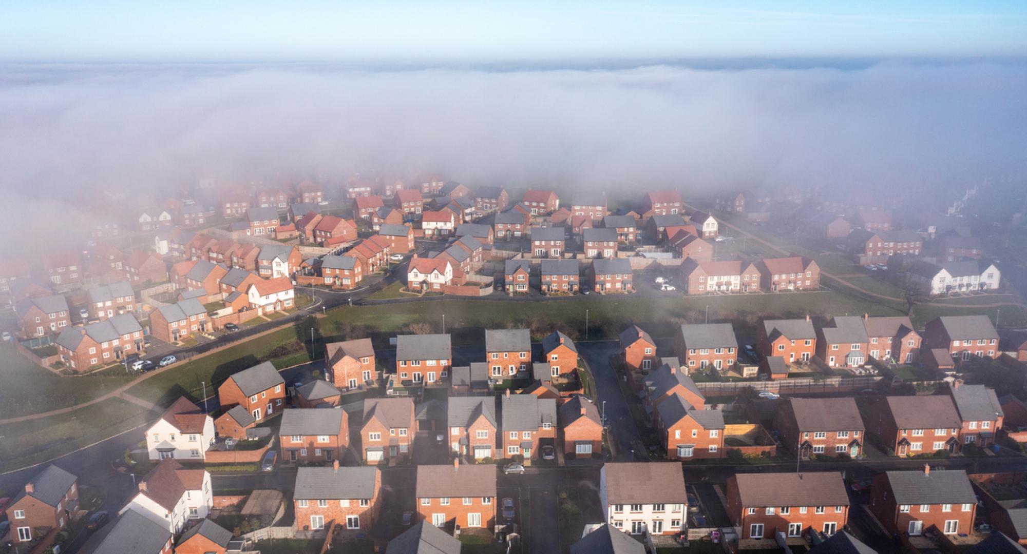 New estate with typical British houses and green gardens hidden by clouds