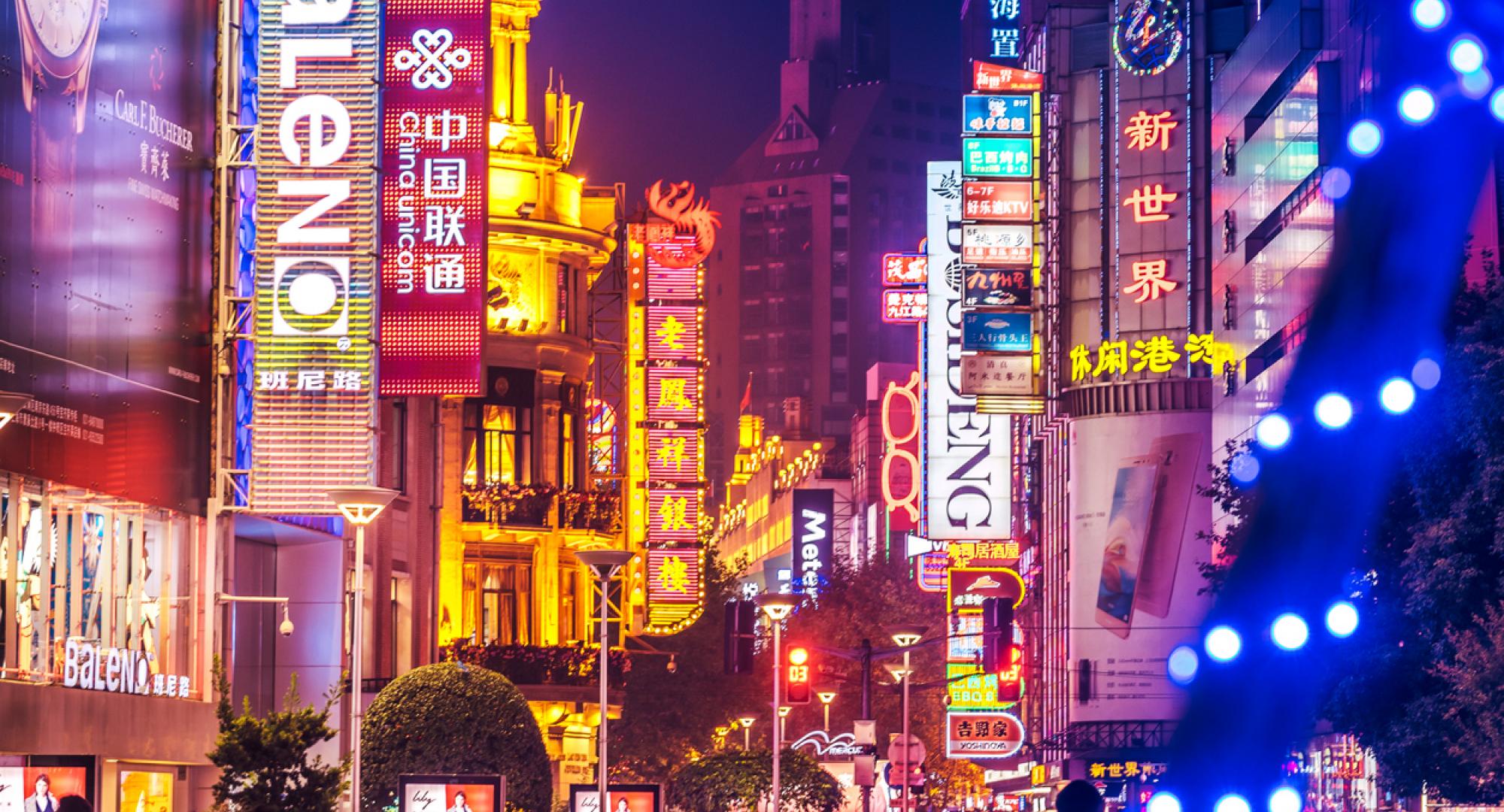 Crowds walk below neon signs on Nanjing Road, Shanghai