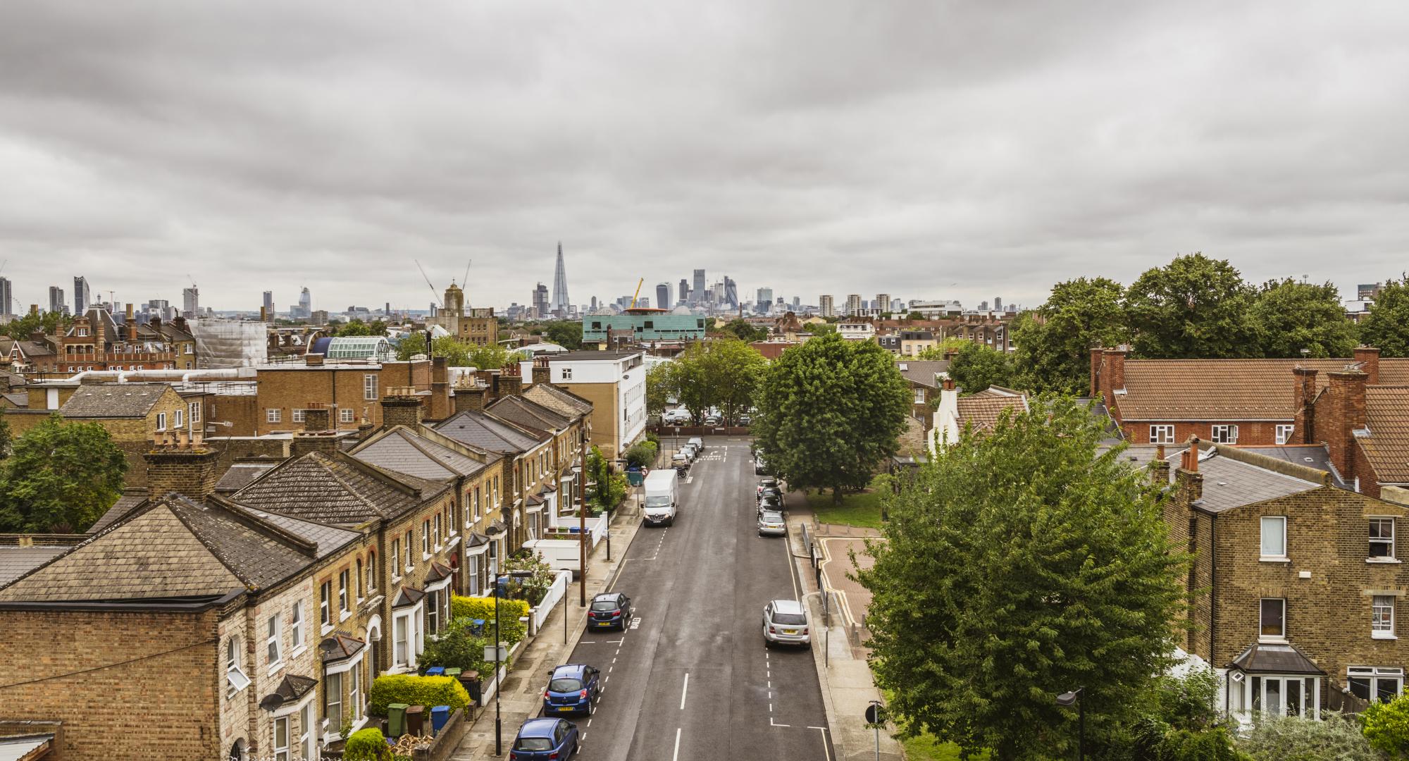 Peckham street with residential housing and the city skyline with skyscrapers on the horizon.