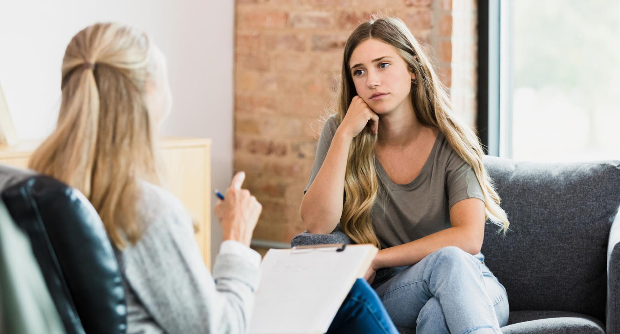 Teen girl listens to advice from unrecognizable female therapist