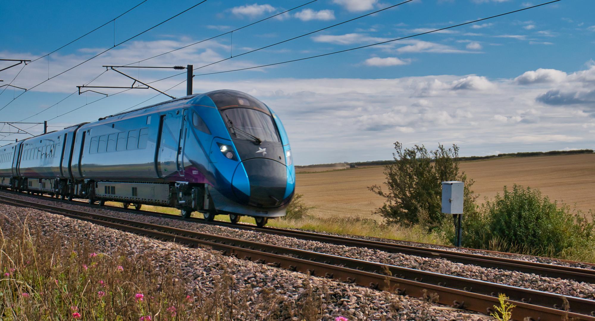 Transpennine Express train travelling at speed in Northumberland, UK - taken on a sunny day with white clouds.