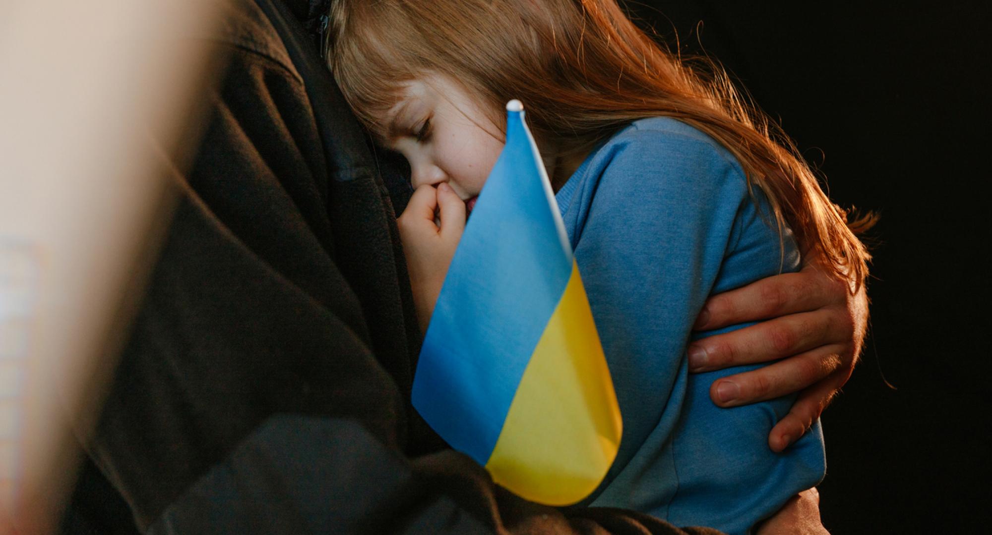 A Ukrainian refugee child with a Ukraine flag