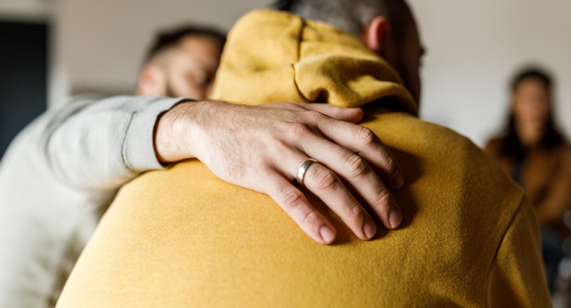 Close up shot of compassionate man embracing his friend