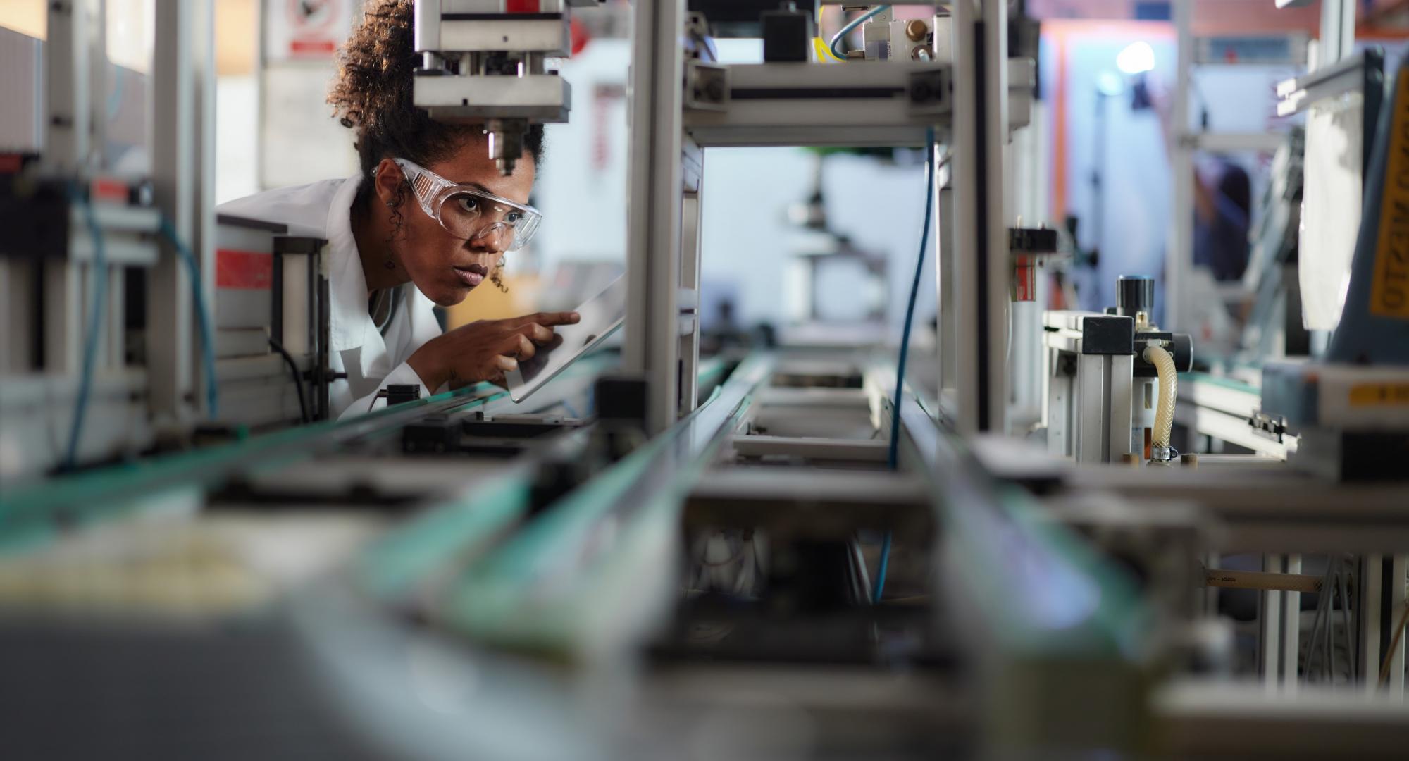 Young scientist using touchpad while working on machinery in a lab