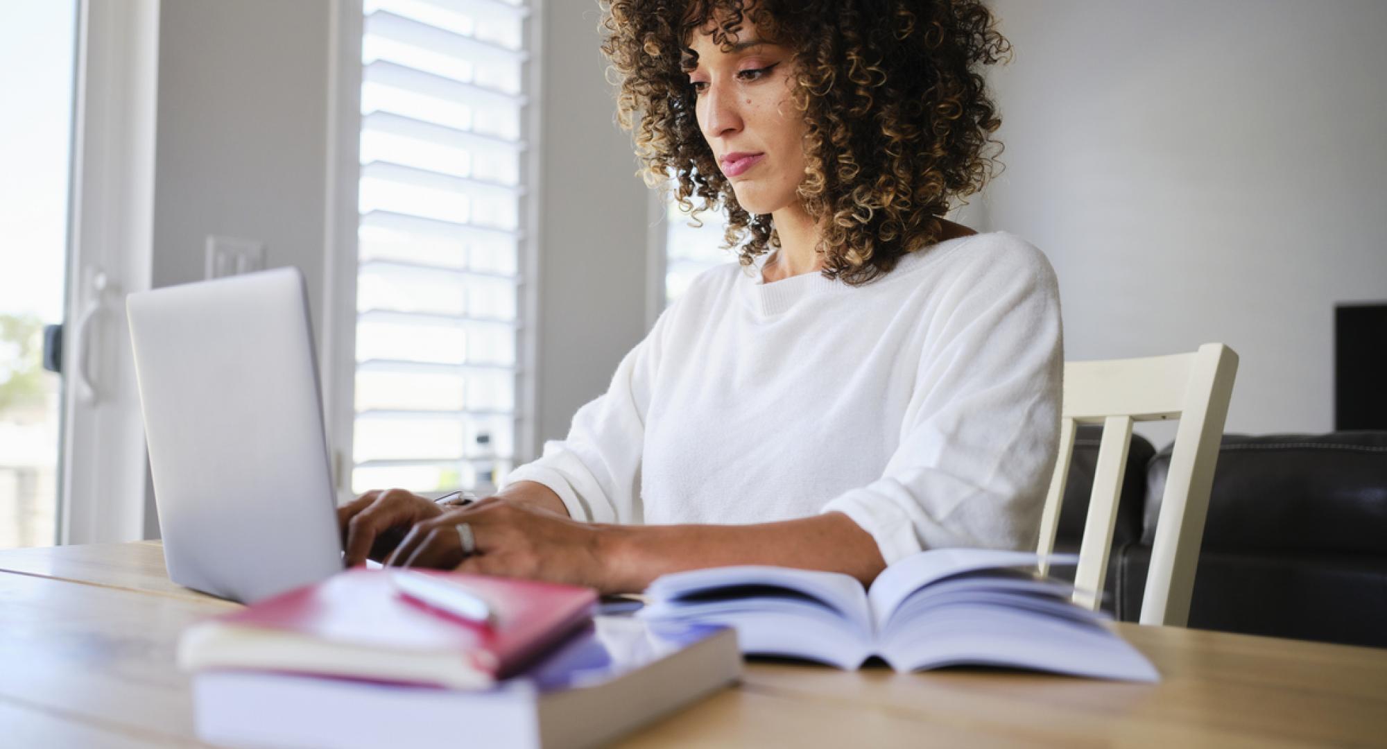 A young woman studying with a laptop computer in a home.