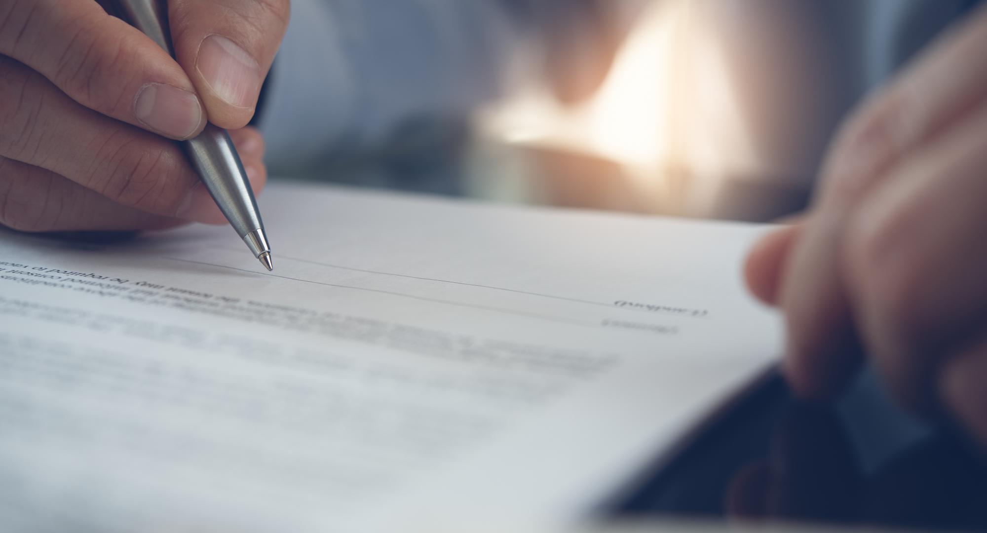 Businessman with pen in hand reading official business contract