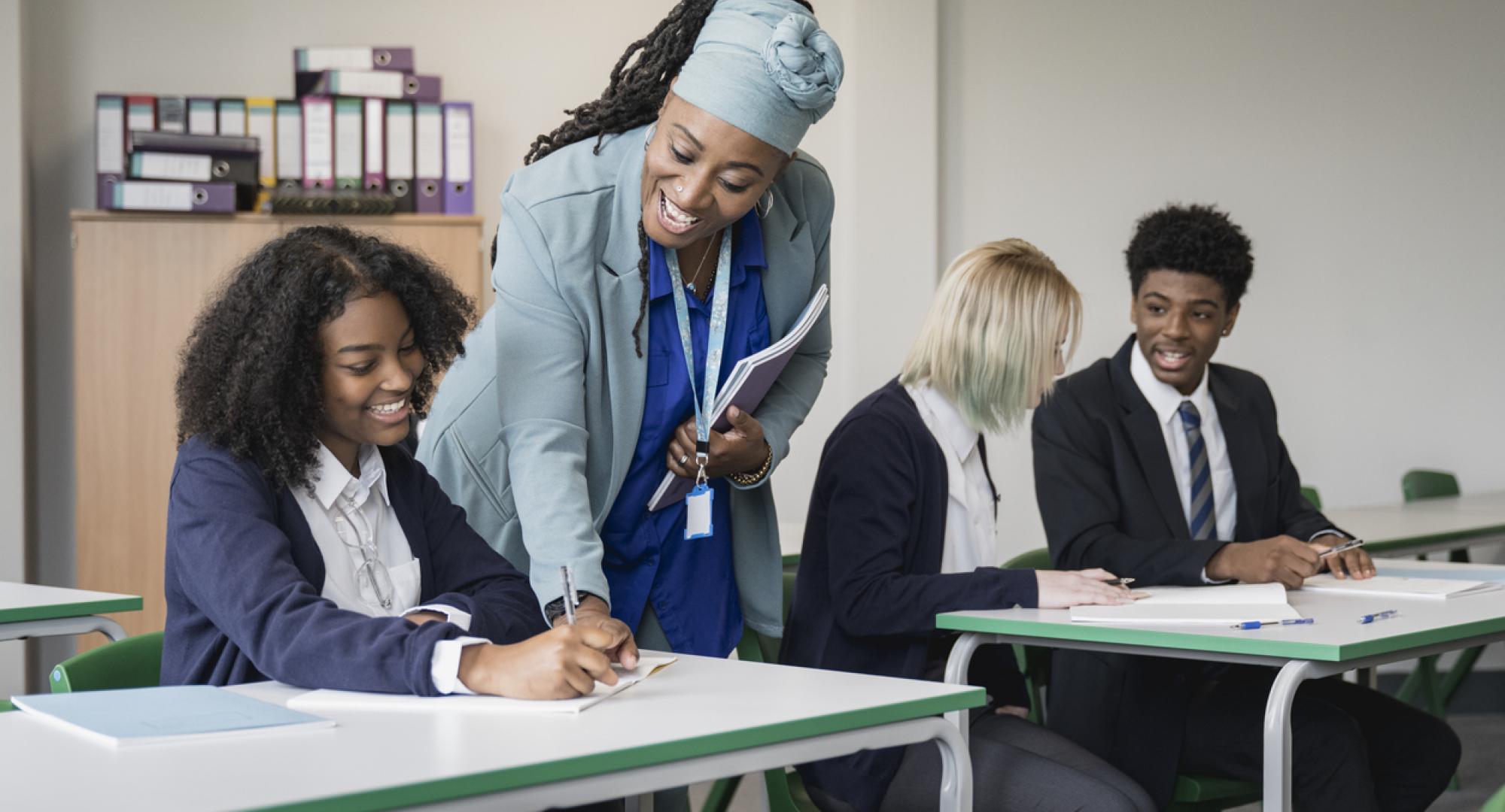 Multiracial group of teenagers in uniforms sitting together at desks