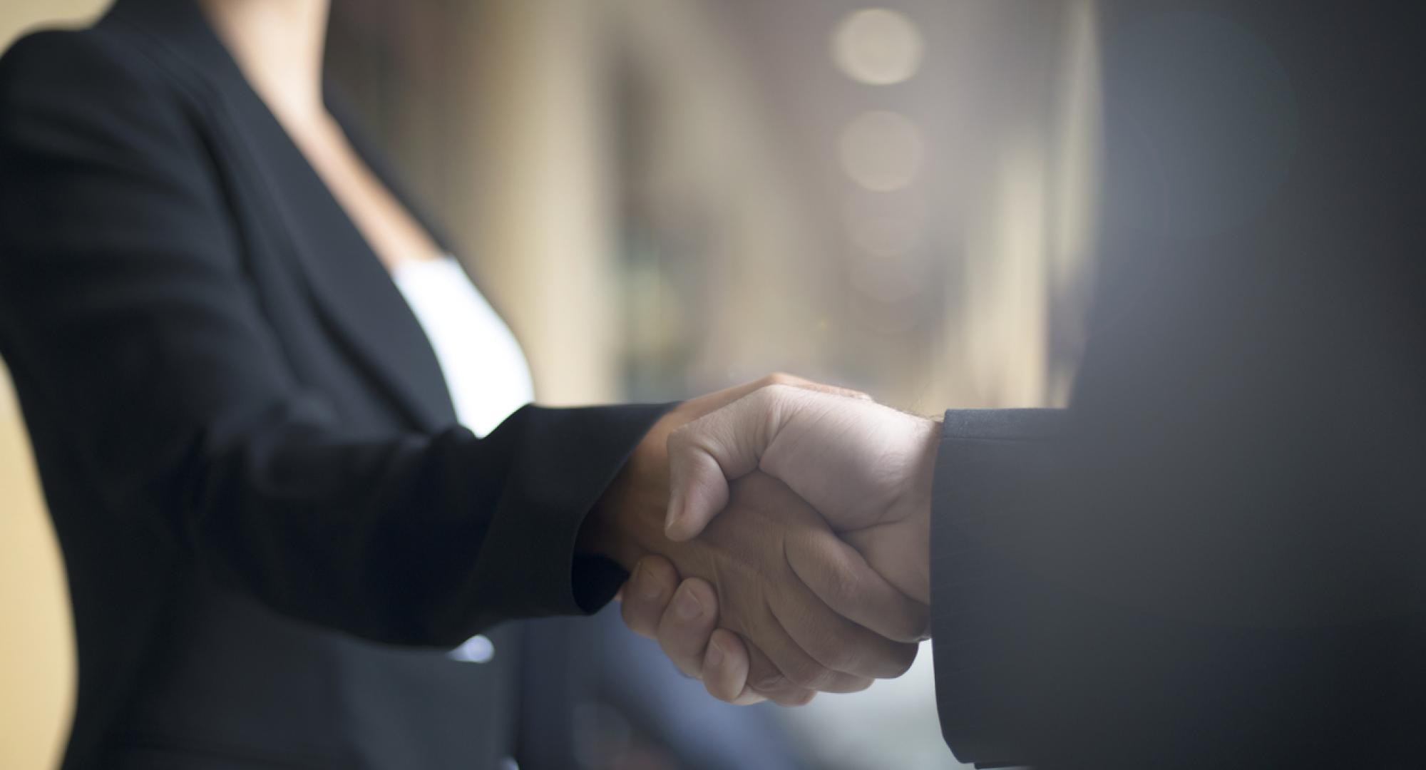 Two people shaking hands on business event.