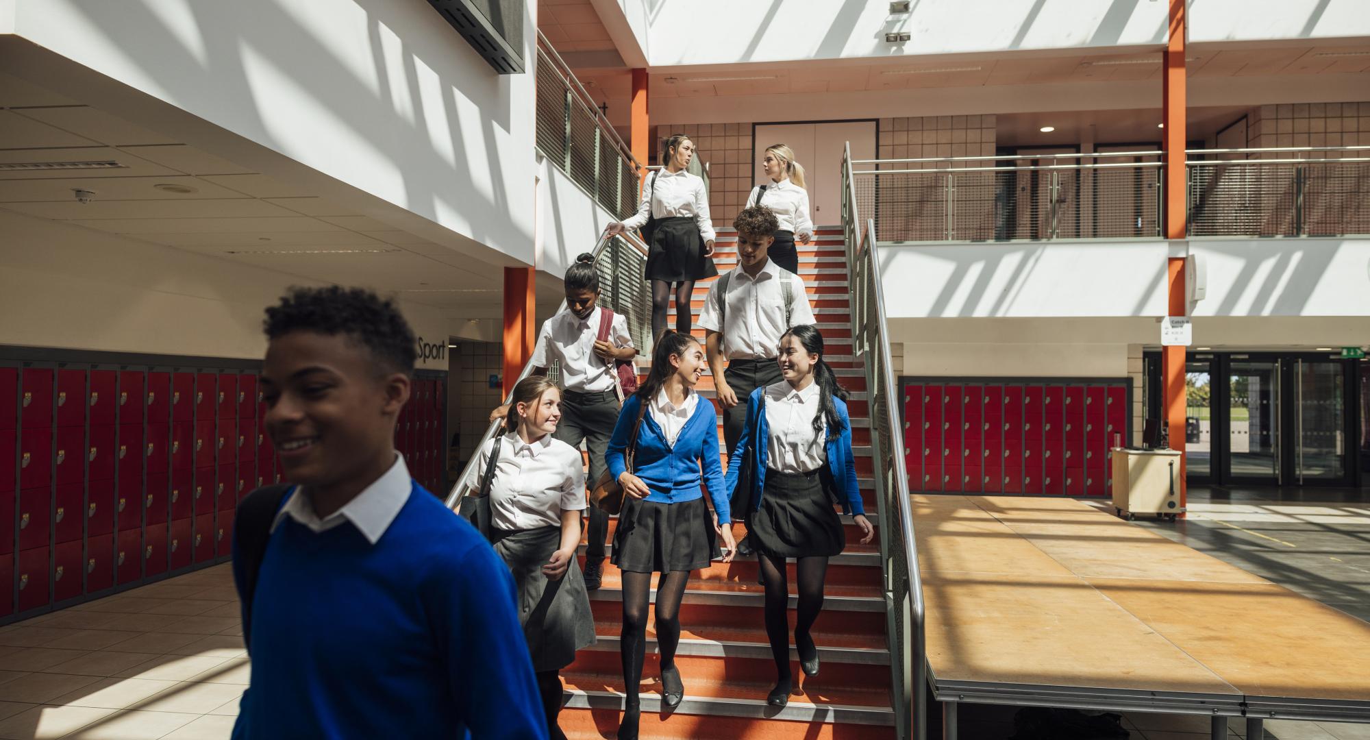 A wide angle view of a group of high school students who are rushing to their next class