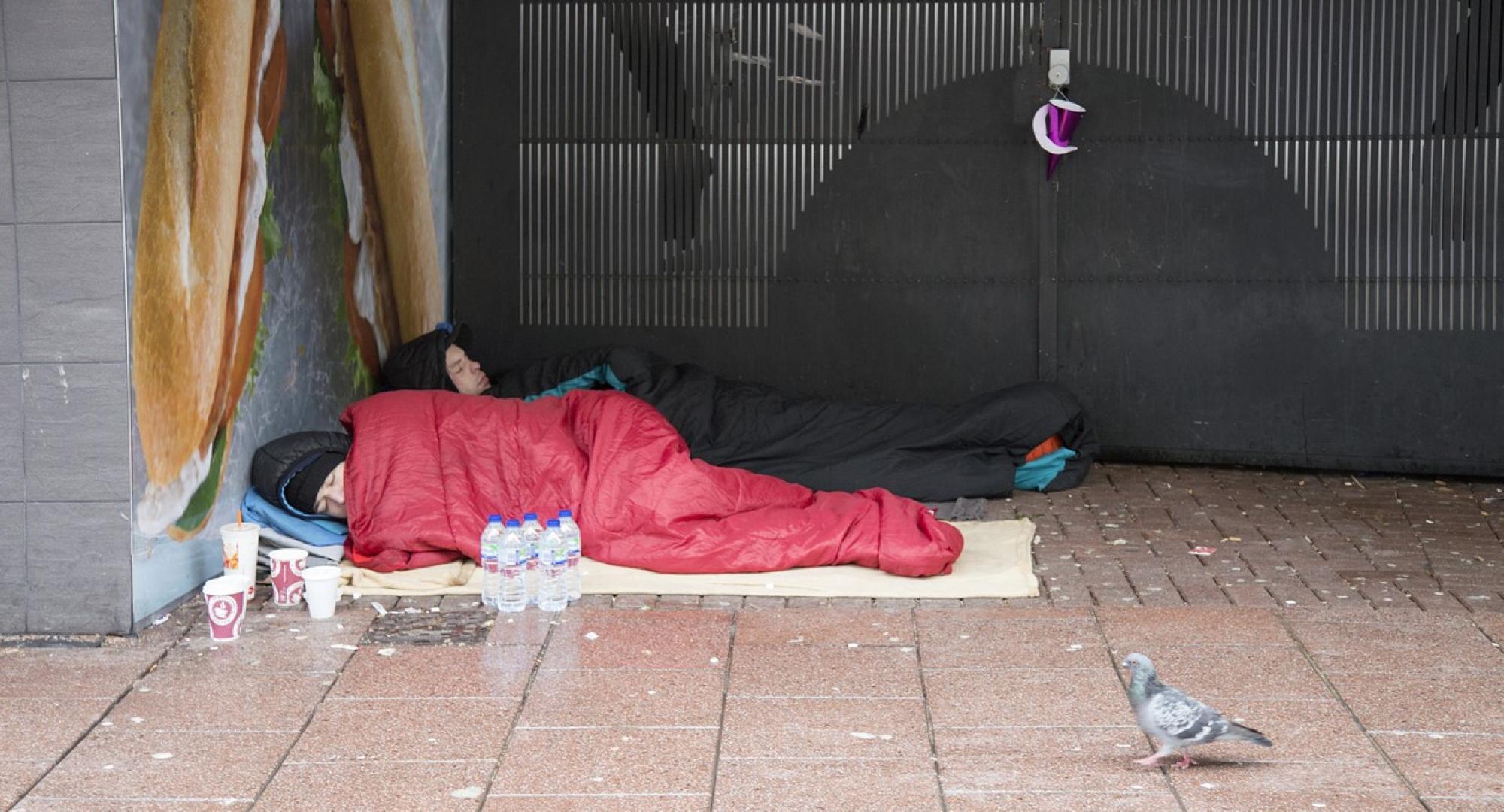 A homeless couple are sleeping in a doorway.