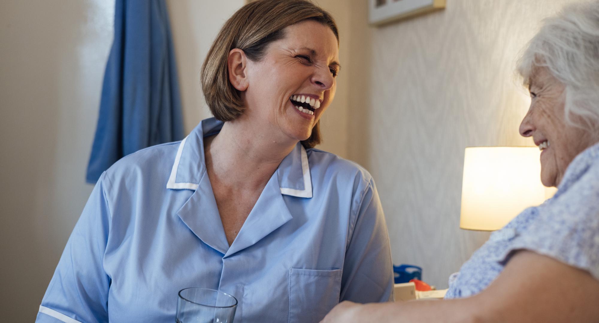 Nurse sat next to an older woman's bed