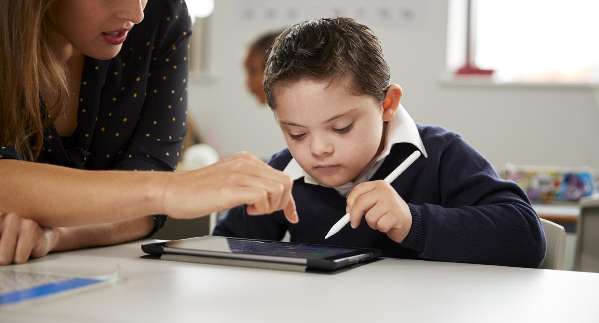 Young female teacher working with a Down syndrome schoolboy