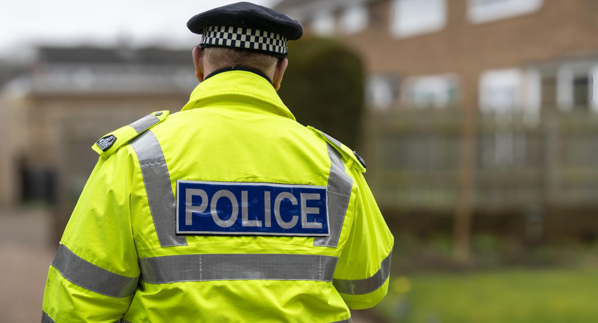 A policeman walking away from an elderly person's home.