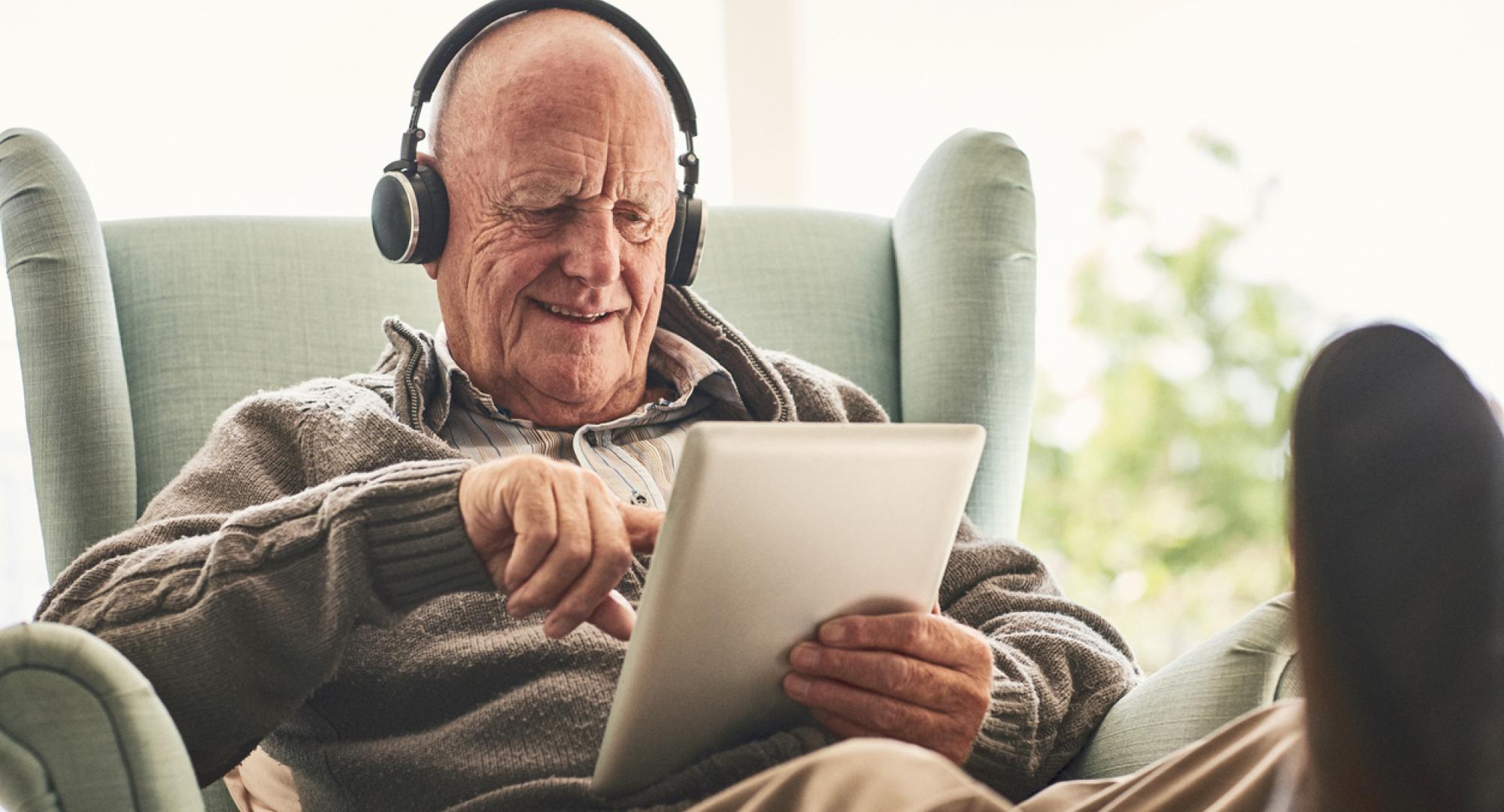 Happy elderly man at home using digital tablet
