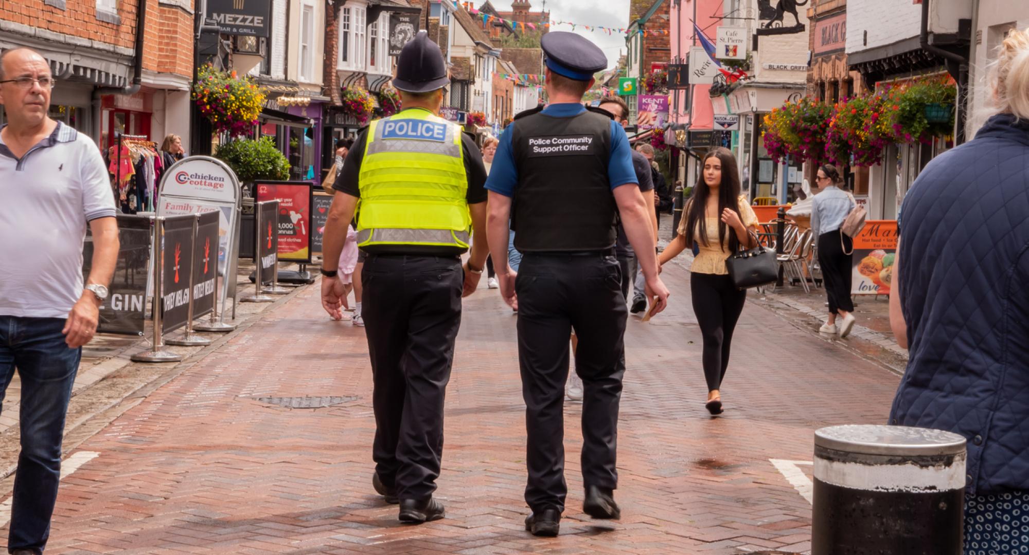 Policeman and Police Community Support Officer walking down a busy street