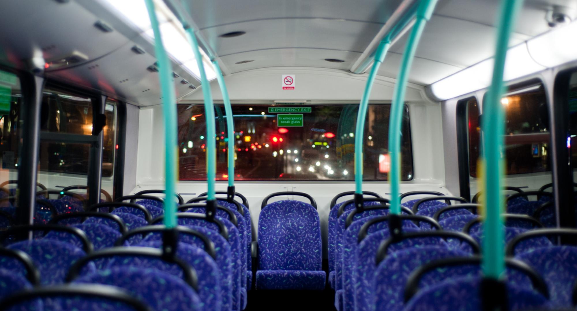 Rows of empty blue seats on a London Double Decker Bus at night