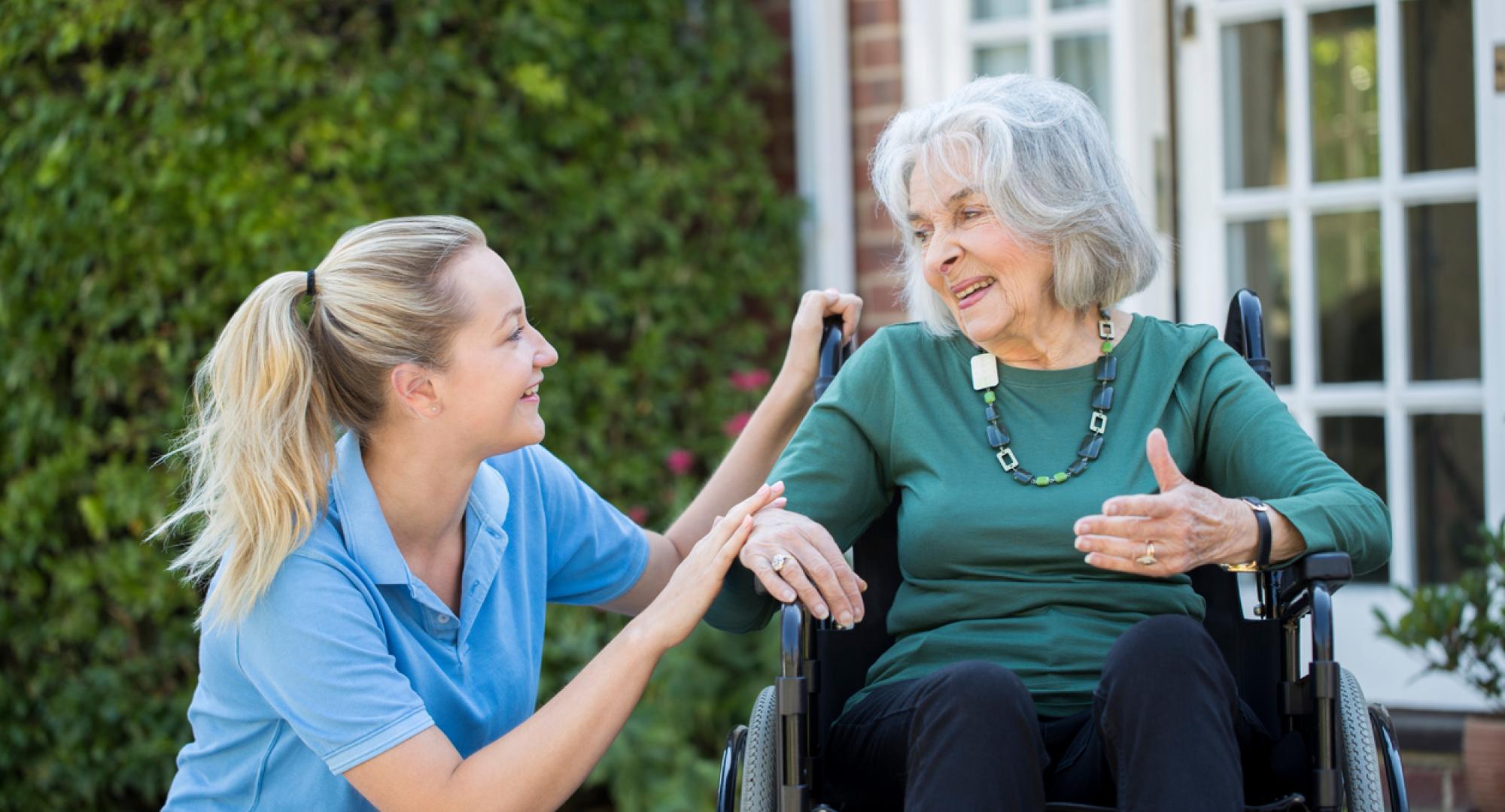 Carer supporting an elderly woman in a wheelchair