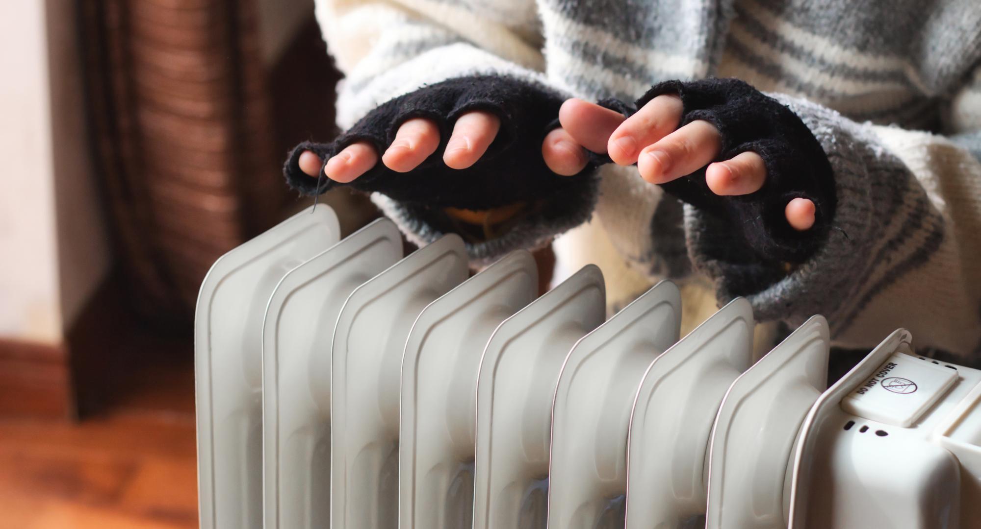 Woman heating her hands in her cold home