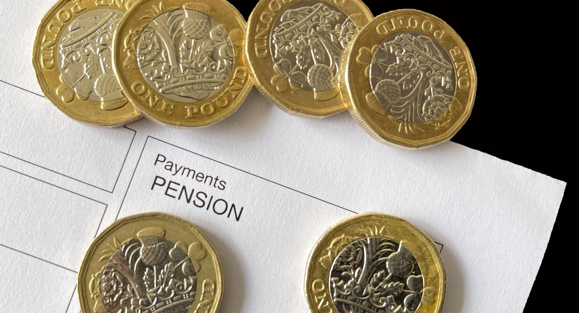 pound coins on top of an anonymous pension payment slip