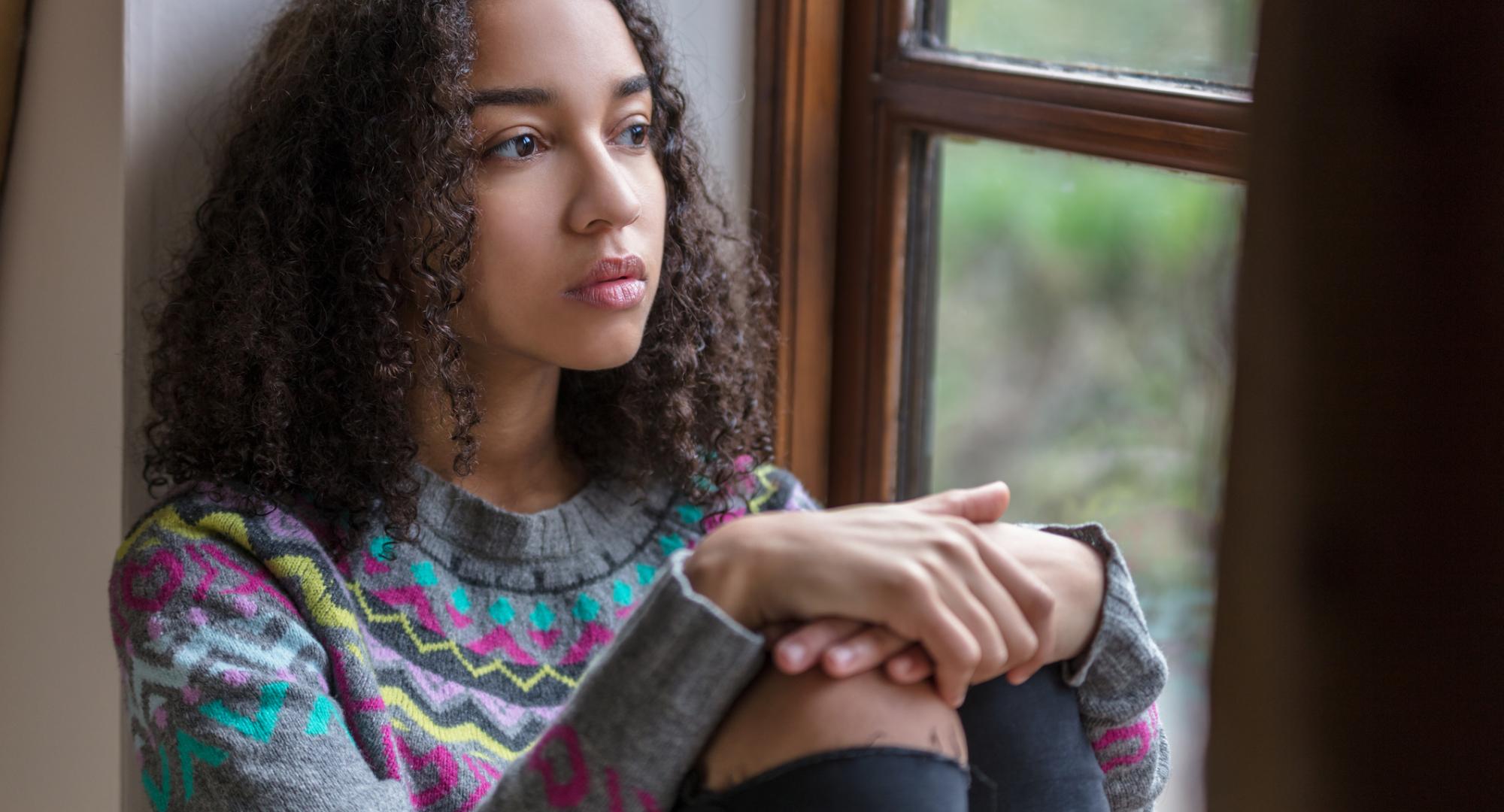 Vulnerable child sitting by window