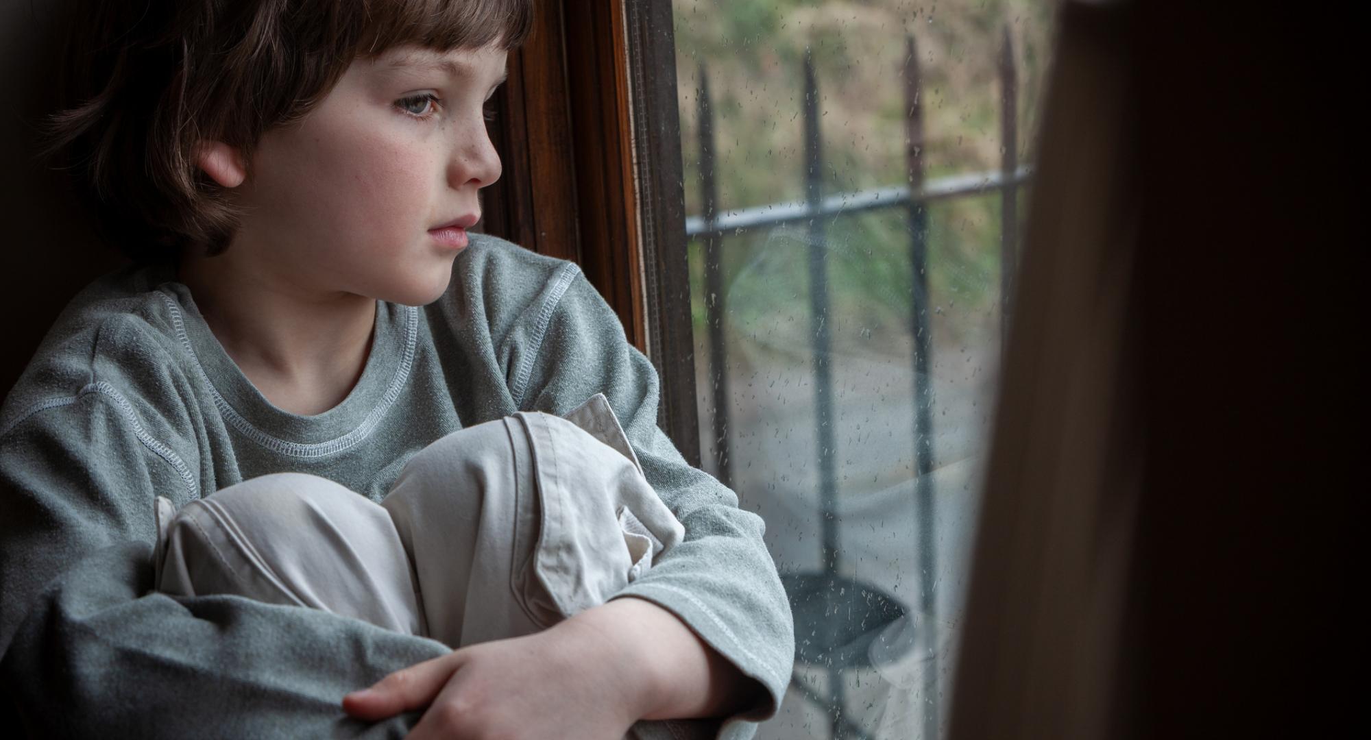 Young boy looking out of window