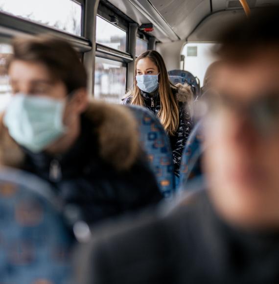 Woman in mask on a bus blurred focus foreground