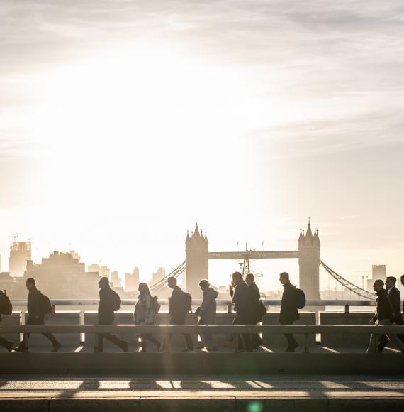 Morning rush hour across London Bridge at dawn. Bright sunlight and Tower Bridge in the background