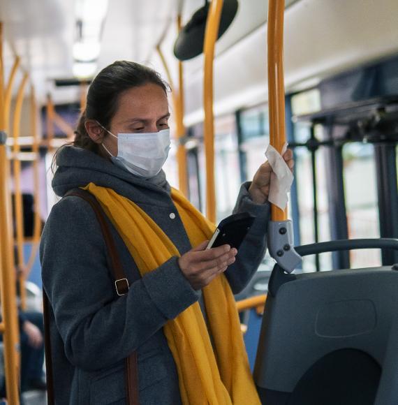 Woman stands  on bus in mask