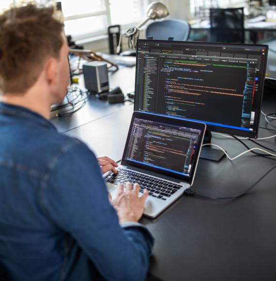 Man sits at computer coding.