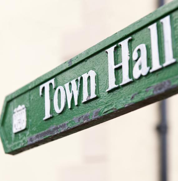 Close-up of a traditional, worn sign showing the direction to the town hall.