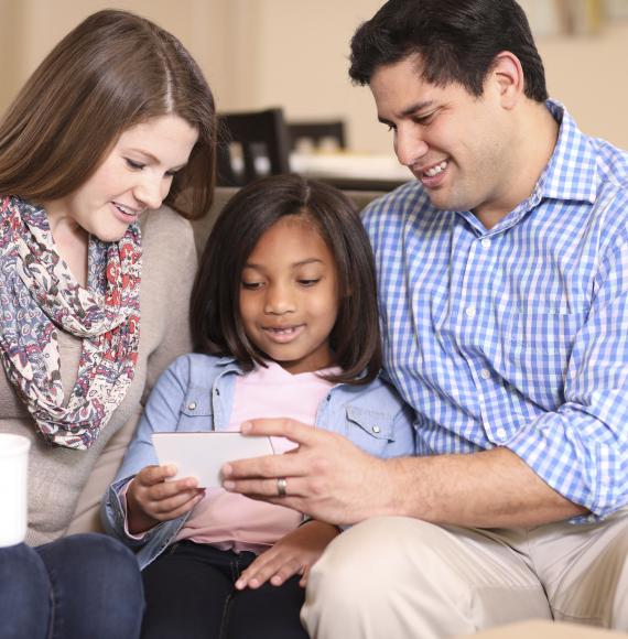 Adopted child sits with parents who are of a different race.