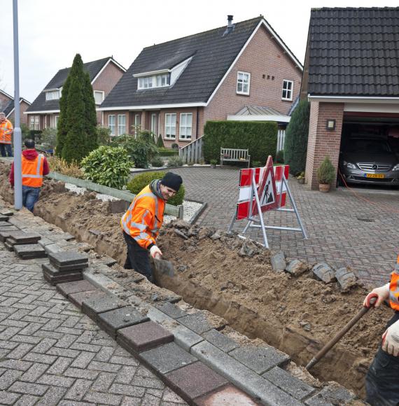 Workmen bring up pavement to lay fibre optic cables.