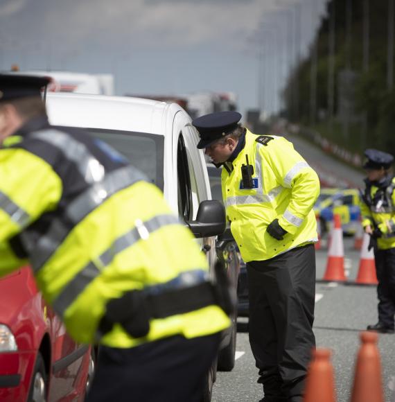 Police officers checking cars through the window. 