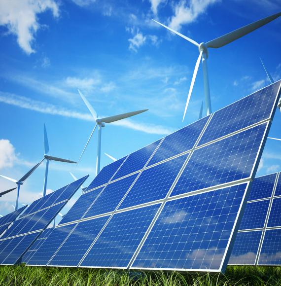 Solar plant in the sun with wind turbines in the backgroud.