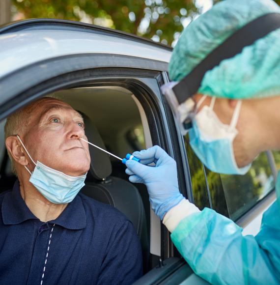 Man receives Covid-19 test from woman wearing full PPE