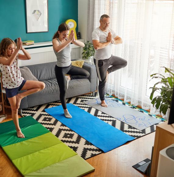 Father and his two daughters practicing yoga with online classes.