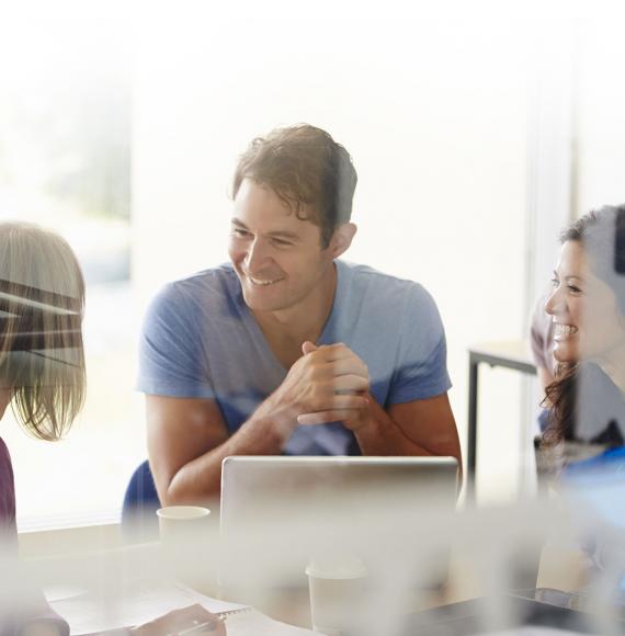 Colleagues sit and chat over office work.