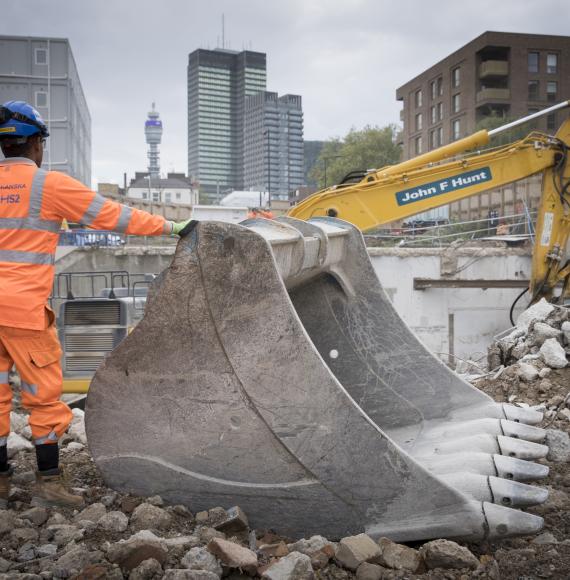 Man stands next to digger working on HS2 at London Euston