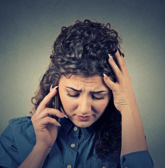 Woman looks distressed on the phone to helpline.