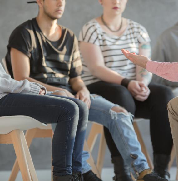 Counsellor sat talking with young people about mental health. 