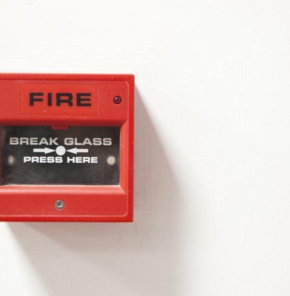 Fire alarm sits on wall ready to be activated. 