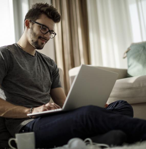 Man sits on his laptop at home doing online course.