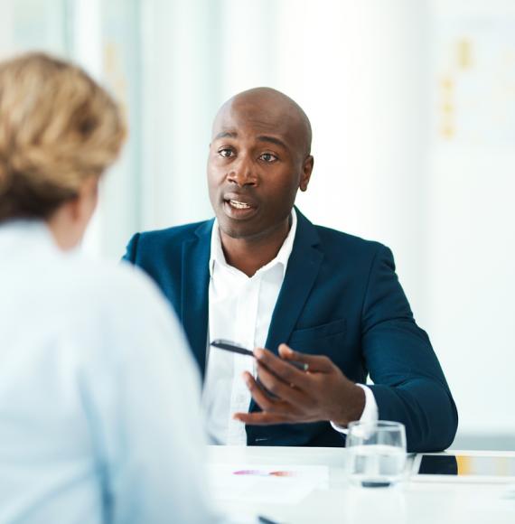 Man gives legal advice to woman in his office. 