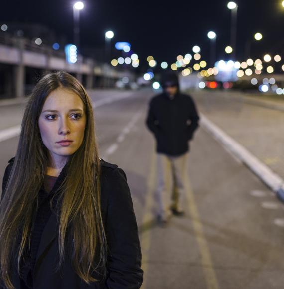 Woman walking alone with man walking behind