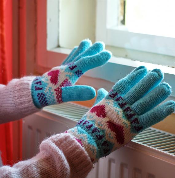 Person wearing gloves over radiator