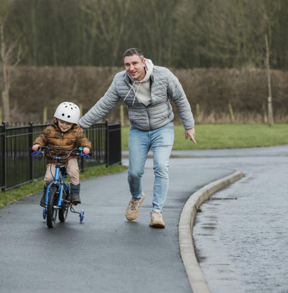 Young boy learning to ride a bike with his dad