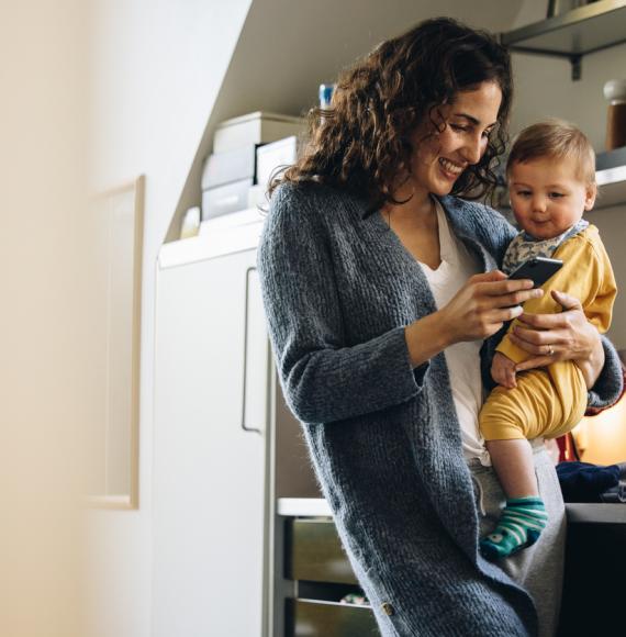 A mother holding a baby and a phone