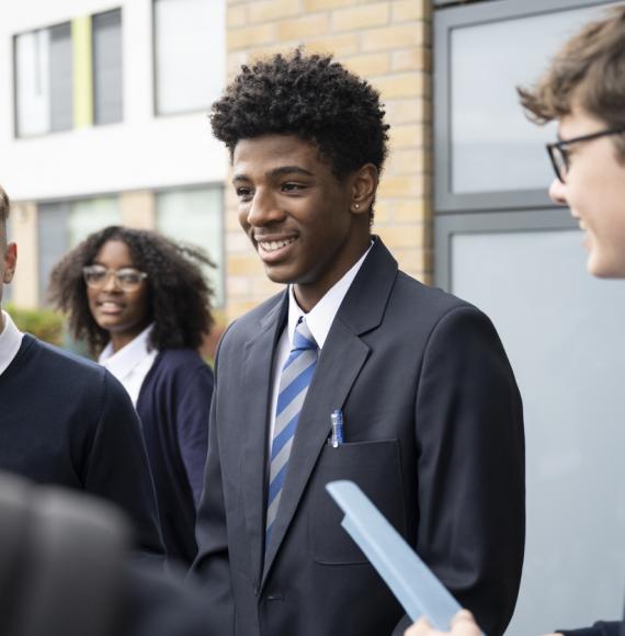 A diverse set of secondary school pupils stood outside a classroom 