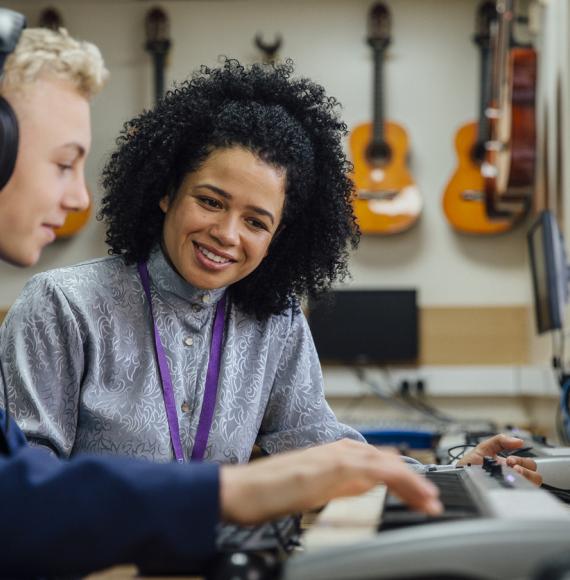 A teacher helping a male student learn to play the keyboard